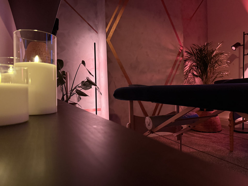 Candlelight and pink wall lighting beside the massage beds